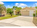 Inviting single-story home with a spacious driveway and lush tropical landscaping, featuring mature palms at 11284 Hickory Ridge Ct, Spring Hill, FL 34609