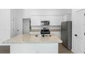 Well-lit kitchen showcases a granite island, white cabinets, and modern stainless steel appliances and finishes at 116 Hallam Ct, Spring Hill, FL 34606