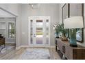 Bright foyer with a decorative door, wooden floors, and a stylish console table with a mirror at 17466 Nokota Ave, Hudson, FL 34667