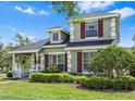 Charming two-story home with lush landscaping, covered porch, and red window shutters at 20053 Heritage Point Dr, Tampa, FL 33647