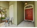 Cozy front porch with seating and a view of the red front door at 25304 Lexington Oaks Blvd, Wesley Chapel, FL 33544