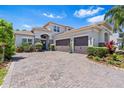 Lovely two-story home featuring a three-car garage, paver driveway, and manicured landscaping at 31050 Spruceberry Ct, Wesley Chapel, FL 33543