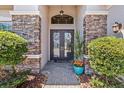 Elegant front door with decorative wreaths, stone accents, and manicured landscaping at 31050 Spruceberry Ct, Wesley Chapel, FL 33543