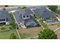 Aerial view of backyard with screened-in pool and lush green lawn surrounded by a white picket fence at 3142 Stonegate Falls Dr, Land O Lakes, FL 34638