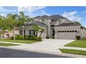 Charming two-story home showcasing a three-car garage and attractive landscaping with palm trees and shrubbery at 3142 Stonegate Falls Dr, Land O Lakes, FL 34638