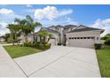Beautiful two-story home featuring a three-car garage, well-manicured lawn, and lush tropical landscaping at 3142 Stonegate Falls Dr, Land O Lakes, FL 34638