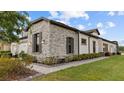Stunning home exterior showcasing stone details, professionally landscaped grounds, and neutral colors at 4354 Barletta Ct, Wesley Chapel, FL 33543