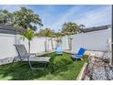Landscaped backyard featuring green turf, lounge chairs, palm trees, and a white privacy fence at 4847 Harbor Woods Dr, Palm Harbor, FL 34683