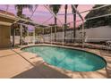 Beautiful kidney-shaped pool enclosed in a screened lanai with a white fence backdrop at 4847 Harbor Woods Dr, Palm Harbor, FL 34683