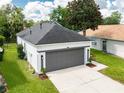 A view of the side of a white house with a gray roof, gray garage door, and well manicured landscaping at 6116 Skylarkcrest Dr, Lithia, FL 33547