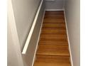 A well lit staircase with hardwood floors and a white handrail leads upwards between gray painted walls at 716 Seagate Dr # 716, Tampa, FL 33602
