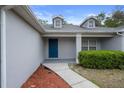 Inviting front entry with a blue door, tidy landscaping, and a well-maintained walkway at 8408 Nuzum Rd, Brooksville, FL 34613