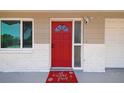 Close-up of the bright red front door with security features and an inviting welcome mat at 10817 Kingsbridge Rd, Port Richey, FL 34668