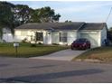 Charming single-story home with a well-maintained lawn and a long concrete driveway with a red car at 12328 Shafton Rd, Spring Hill, FL 34608
