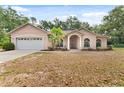 Inviting single-story home with arched entryway, two-car garage and mature landscaping at 15703 Walden Ave, Tampa, FL 33618