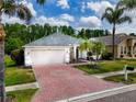 Charming single-story home with a two-car garage, red brick driveway, mature landscaping and lawn at 16113 Rambling Rd, Odessa, FL 33556