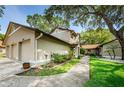 Exterior view showcases attached two car garage, mature trees, and beautiful landscaping at 1647 Hamilton Ct, Dunedin, FL 34698
