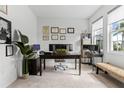Bright home office features carpet flooring, a large desk, and natural light from the window at 16633 Goose Ribbon Pl, Wimauma, FL 33598