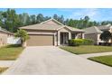 Single-story home with a manicured lawn, two car garage, and mature landscaping at 19528 Sunset Bay Dr, Land O Lakes, FL 34638