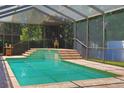 A tranquil pool with tiled steps within a screened enclosure at 2642 Meadow Wood Dr, Clearwater, FL 33761