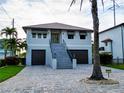 Two-story home featuring a paved driveway, two car garage, palm tree and stairway to front door at 3924 N Ridge Ave, Tampa, FL 33603