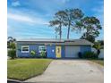 Charming single-story blue home featuring solar panels, a yellow front door, and a well-maintained front yard at 4511 Huntington Ne St, St Petersburg, FL 33703