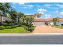 Suburban home featuring a red tile roof, two-car garage, and brick driveway, plus manicured lawn at 4815 Queen Palm Ne Ter, St Petersburg, FL 33703