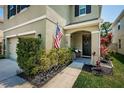 Charming front porch with an American flag, dark door, dark mulch beds, and manicured green bushes at 5928 81St N Ave, Pinellas Park, FL 33781