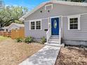 Close-up view of a charming single-story home showcasing a blue door and tidy front yard at 8114 N 11Th St, Tampa, FL 33604