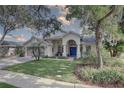 Charming home featuring a stucco exterior, well-manicured lawn, and a welcoming blue front door at 1069 Captains Way, Tarpon Springs, FL 34689