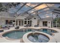 Inviting outdoor pool area featuring a spa, ample seating, and a screened enclosure at 1069 Captains Way, Tarpon Springs, FL 34689