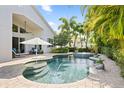 Resort-style pool with a fountain, lush landscaping, and an umbrella-covered seating area at 13135 Plantation Ter, Seminole, FL 33776
