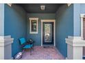 Inviting entryway with a blue accent wall, brick flooring, and a cozy seating area by the black-framed glass door at 16930 Red Brick Ln, Land O Lakes, FL 34638