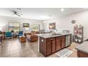 Open-concept living space with tiled floors, island kitchen, comfortable sofa, and dining area with natural light at 16930 Red Brick Ln, Land O Lakes, FL 34638