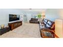 Spacious living room featuring neutral tile floors, a large leather sofa, and abundant natural light at 1859 Northview Rd, Largo, FL 33770