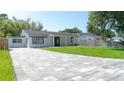 Charming home featuring a gray brick driveway, manicured green lawn and a light gray exterior paint at 2288 Cheryl Rd, Largo, FL 33771