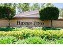Community sign with lush landscaping, reading 'Hidden Pines: A deed restricted community' at 2486 Hickman Cir, Clearwater, FL 33761