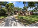Exterior view showcasing a long, paved driveway leading to a cozy single-story home with a lush green lawn at 2932 Chelsea Woods Dr, Valrico, FL 33596