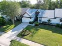 Beautiful single-story home with an attached two-car garage, lush green lawn, and mature trees at 1353 Camelot Ct, Palm Harbor, FL 34684