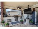 Covered outdoor summer kitchen with granite counters, stainless grill, and outdoor television at 13878 Allamanda Cir, Port Charlotte, FL 33981