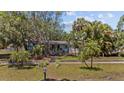 Landscaped front yard with mature trees and a charming single-story home featuring a blue trimmed roof and door at 3025 50Th St S S St, Gulfport, FL 33707