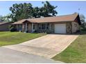 Exterior of a charming home featuring a large driveway, attached garage, and well-maintained landscaping at 31258 Park Ridge Dr, Brooksville, FL 34602