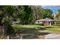 A single-story brick home with a spacious front yard and mature trees at 38327 Palm Grove Dr, Zephyrhills, FL 33542