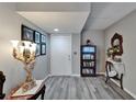 A foyer with gray wood floors, a decorative table lamp and an antique bookshelf with Gathering photos on the wall at 4709 Puritan Cir # 702, Tampa, FL 33617