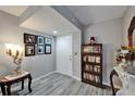 A foyer with gray wood floors, a decorative table lamp and an antique bookshelf with Gathering photos on the wall at 4709 Puritan Cir # 702, Tampa, FL 33617