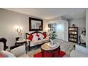 A living room decorated with a white sofa and chair set, a red rug, gray walls, and gray wood floors at 4709 Puritan Cir # 702, Tampa, FL 33617