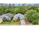 Aerial view showcasing the home's landscaped yard, neighborhood, and surrounding trees at 5143 New Brittany Ln, Zephyrhills, FL 33541