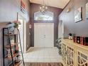 Inviting foyer featuring tile flooring, a decorative chandelier, and a view of the double front doors at 5143 New Brittany Ln, Zephyrhills, FL 33541
