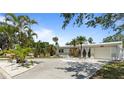 Charming single-story home featuring a well-manicured lawn and tropical landscaping with a light grey painted exterior at 8347 41St N Ave, St Petersburg, FL 33709