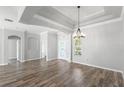 Bright living room featuring tray ceilings, hardwood floors, and modern chandelier at 12925 Tar Flower Dr, Tampa, FL 33626